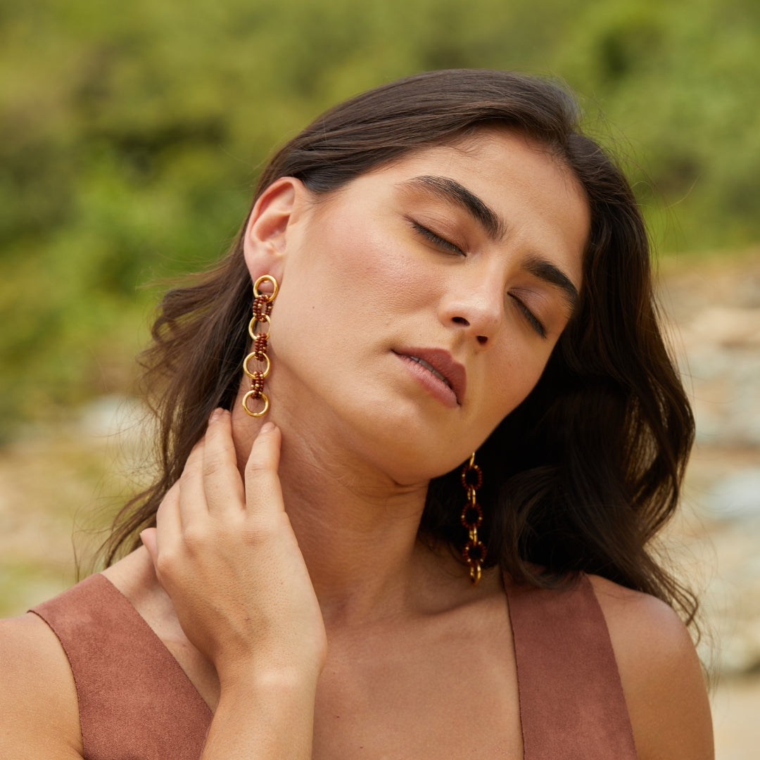 Aretes largos entrelazados tejidos con marrón y dorado en modelo