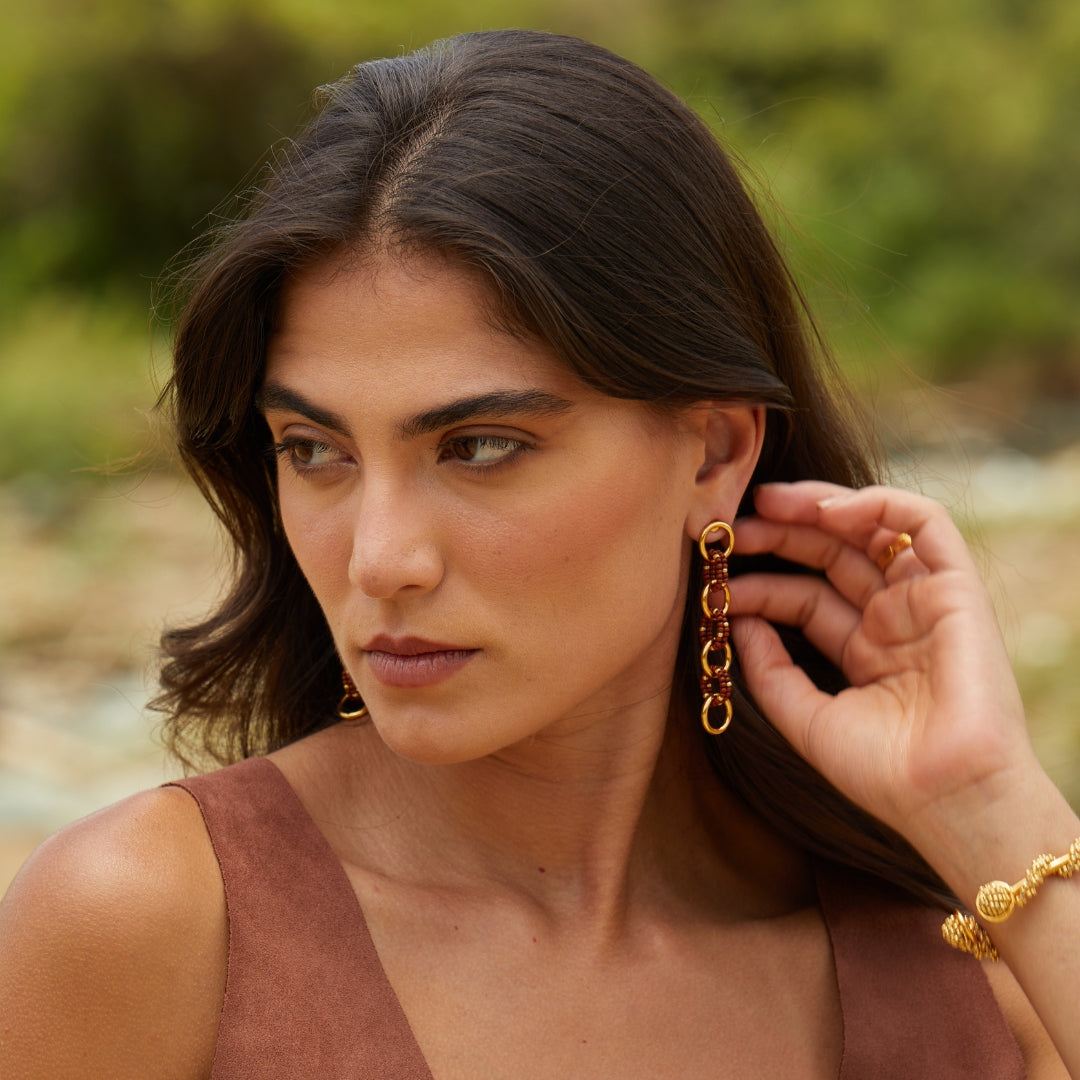 Aretes largos entrelazados tejidos con marrón y dorado en modelo