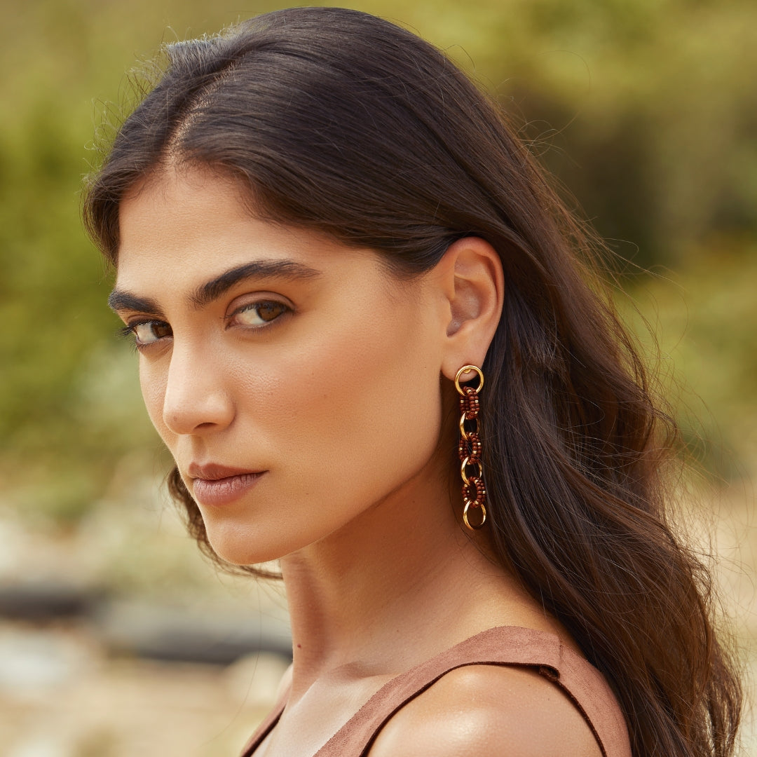 Aretes largos entrelazados tejidos con marrón y dorado en modelo