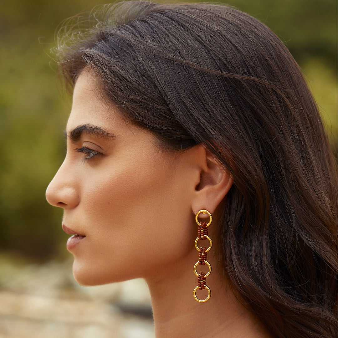 Aretes largos entrelazados tejidos con marrón y dorado en modelo
